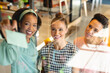© Wavebreak Media - Smiling multiracial female colleagues discussing business plan on glass wall in office
