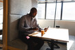 © Wavebreak Media - African american mature businessman using smart phone while having coffee during break in office