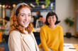 © Wavebreak Media - Portrait of smiling caucasian young businesswoman with female colleague in creative office