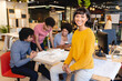 © Wavebreak Media - Portrait of smiling female architect sitting on table while colleagues discussing in background