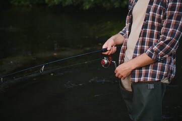 Fisherman catches a trout on the river in summer