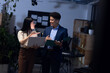 © Wavebreak Media - Asian male and female professionals with laptop and report discussing data in office at night