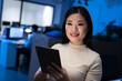 © Wavebreak Media - Portrait of smiling asian businesswoman using digital tablet while working late in modern office