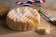 Aged French soft cheese with orange washed rind from the Vosges mountain range on a cutting board close up with french flags in the background 
