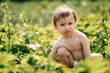 © Ananass - a little girl wearing only one diaper tastes sweet ripe strawberries in the village garden