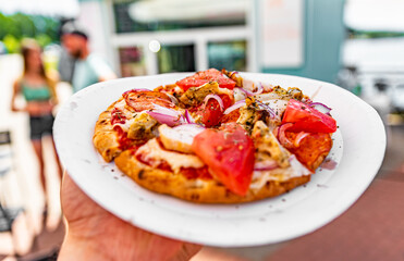 Wall Mural - man holds paper plate with mini pita pizza in hands. Street food, fast food outdoor