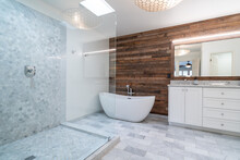 Marble And Wood Bathroom With Free Standing Tub And Wooden Panel Accent Wall