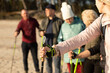 © Татьяна Волкова - Close-up of leader woman and people group making Nordic walking with professional trekking sticks at beach, path travel