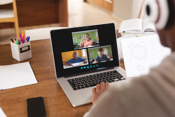 Canvas Print - Multiracial boy looking at students on laptop screen while attending online lecture from home