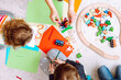 Little kids and educator folding Bricks and drawing with colored pencils sitting on floor in playroom top view. Interesting lesson for kindergartners developing creation and intelligence