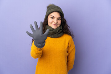 Wall Mural - Teenager Russian girl with winter hat isolated on purple background counting five with fingers