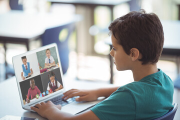 Sticker - Side view of caucasian boy looking at screen with students on video call during online class at home