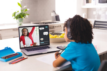 Sticker - African american boy wearing headphones looking at laptop screen with girl student in online class