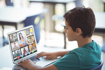 Sticker - Focused caucasian boy looking at screen while attending online class over laptop on table at home