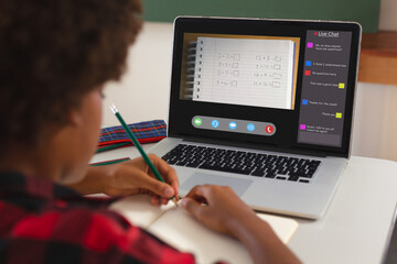 Poster - African american girl with afro hair writing maths in book from laptop screen during online class