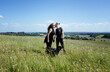 © Cavan Images - lesbian couple kissing whilst walking their dog in a beautiful meadow