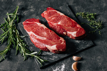 Raw chuck roll beff steaks on dark background