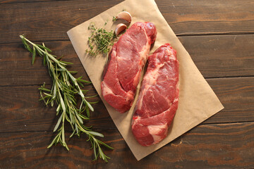 Poster - Raw chuck roll beef steaks on wooden background with rosemary and thyme