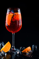 Canvas Print - Shining cocktail Aperol syringe in a wine glass with ice and a slice of orange on a dark background