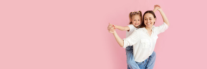 Wall Mural - mom woman in light clothes has fun with cute baby girl. little baby daughter sitting on mother's bac