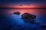 Fototapeta  - Widok skał oblewanych przez morze o wschodzie słońca przy kolorowym niebie
