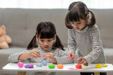 The Little Girl Is Learning To Use Colorful Play Dough In A Well Lit Room