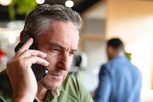 Close-up Of Mature Businessman Talking On Smart Phone In Creative Office