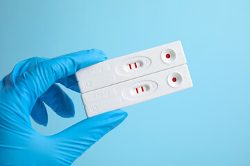 doctor holding two disposable express tests for hepatitis on light blue background, closeup