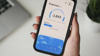 Woman checks her financial expenses using digital banking app. Budget and expense tracking application for mobile phone.