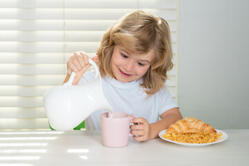 Wall Mural - Pretten child pouring whole cows milk. Kid bot eating meal. Healthy nutrition for children. Child enjoy eating for breakfast or dinner with appetite. Hungry child eat tasty fruits and vegetables.