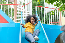 Happy Little African Child Girl Sliding And Playing At Outdoor Playground In The Park On Summer Vacation. Kindergarten Children Kid Enjoy And Fun Outdoor Activity Learning And Exercising At School.