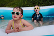 Wet children in the pool wearing sunglasses