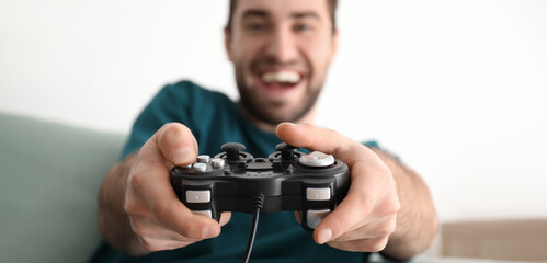 Wall Mural - Young man playing video games at home, closeup