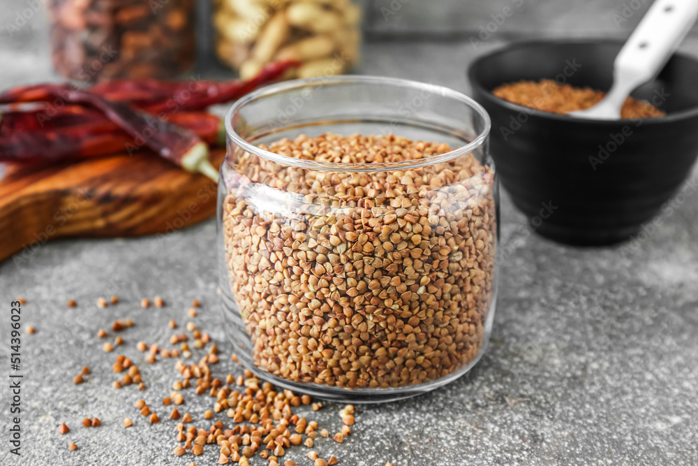 Glass jar with buckwheat grains on grunge table