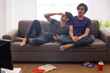 © IndiaPix - Two teenage boys watching TV and having fun together while sitting on sofa in living room