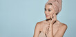 © Peakstock - Happy woman with moisturized fresh skin with towel on head after bath procedures on blue background. Body care concept