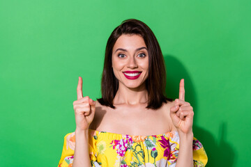 Sticker - Photo of cheerful lovely lady toothy smile direct fingers up empty space isolated on green color background