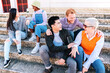 © Jose Calsina - Group of friends enjoying the weekend sitting outdoors. Multiethnic people talking in stairs.