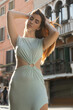 © LIGHTFIELD STUDIOS - low angle view of woman in elegant dress posing with hands behind head and closed eyes in Venice.