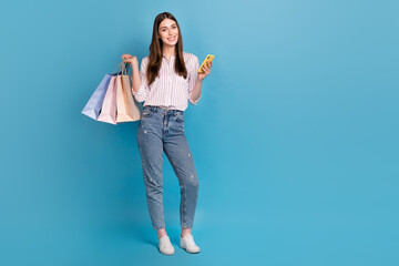 Canvas Print - Full length body size view of attractive cheerful trendy girl holding bags buying app 5g isolated over bright blue color background