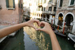 cropped view of tourist showing heart sign on blurred street in Venice.