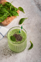 Spinach smoothie healthy green. Vegan smoothie or milkshake from spinach, banana and chia seeds on gray concrete table background. Clean eating, alkaline diet. Top view. Mock up.