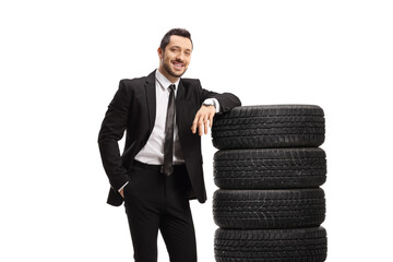 Poster - Man in a suit and tie leaning on a pile of car tires