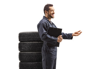 Wall Mural - Auto mechanic with a pile of tires explaining with hand