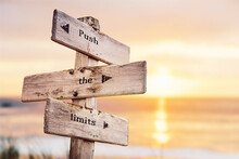 Push The Limits Text Quote On Wooden Crossroad Signpost Outdoors On Beach With Pink Pastel Sunset Colors. Romantic Theme.