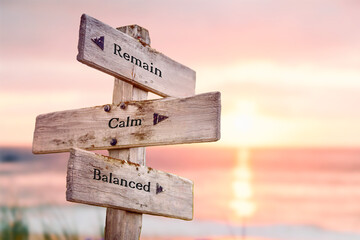 remain calm balanced text quote on wooden crossroad signpost outdoors on beach with pink pastel sunset colors. Romantic theme.