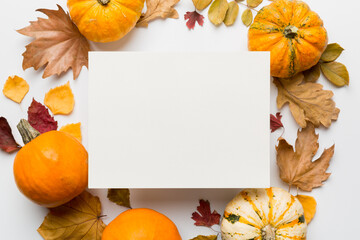 Wall Mural - Autumn composition with paper blank and dried leaves with pumpkin on table. Flat lay, top view, copy space