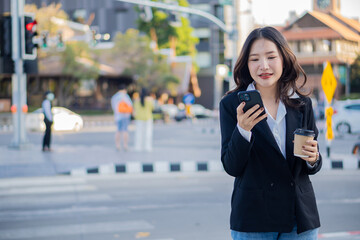 Asian businesswoman working outside on a smartphone looking at a screen in a business district. professional woman sitting outside