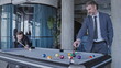 © Synthex - Male business partners playing billiards and discussing cooperation in office