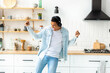 Happy carefree freedom young man in headphones dancing at home in the kitchen alone having fun